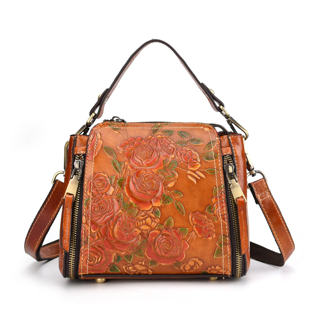 American designer leather handbag with embossed floral pattern and adjustable shoulder strap