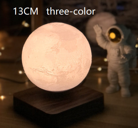 13CM three-color magnetic levitation moon lamp floating above wooden base with astronaut figure in background
