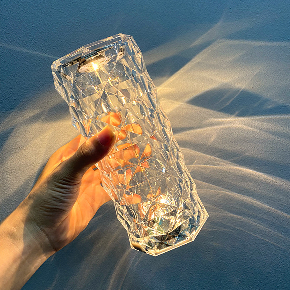 Hand holding a clear Nordic crystal lamp for bedroom casting light patterns on wall