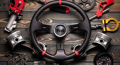 best car interior accessories collection showcasing a sport steering wheel pistons tools and gauge on wood background