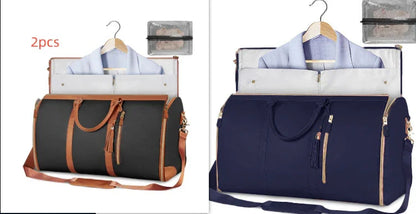 Set of two travel garment bags in black and navy blue with tan and gold accents, featuring suit compartments and handles