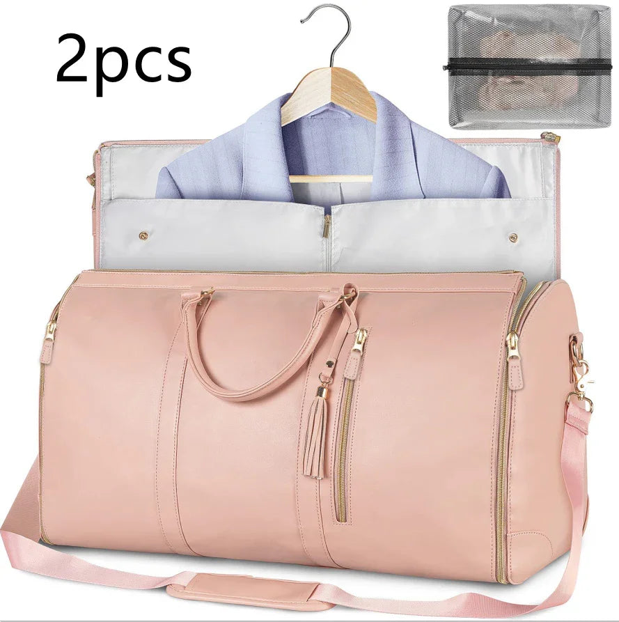Pink leather travel duffel bag with shoulder strap and garment compartment holding a blue blazer