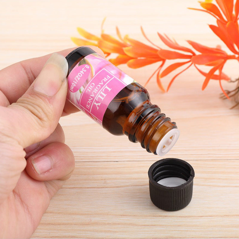 Hand holding a small brown bottle of lily fragrance essential oil for aromatherapy essential oil humidifier