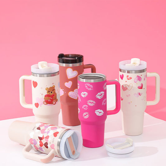 40 oz insulated tumbler with handle featuring colorful heart and bear designs with lids on a pink background