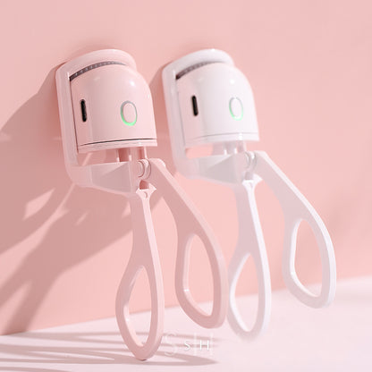 Popmarket electric heated eyelash curler in pink and white with ergonomic handles against a pink background