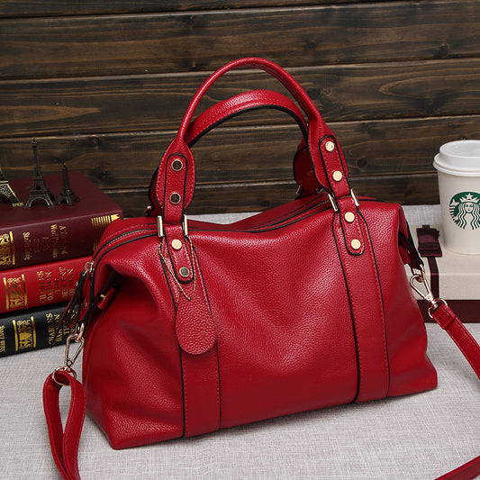 Red handbag on a textured surface with books and a Starbucks cup in the background.