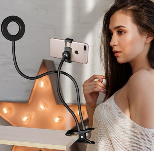 LED selfie ring light with adjustable flexible arms and phone holder clipped to desk for hands-free use