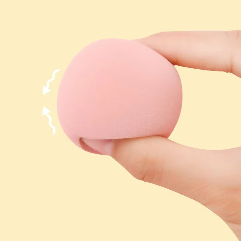 Hand holding a soft pink makeup blender sponge cosmetic puff for foundation application