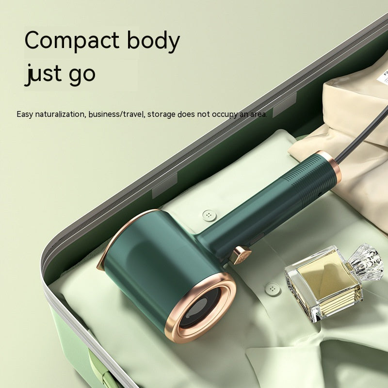Mini handheld garment steamer in green and gold placed inside a suitcase for travel