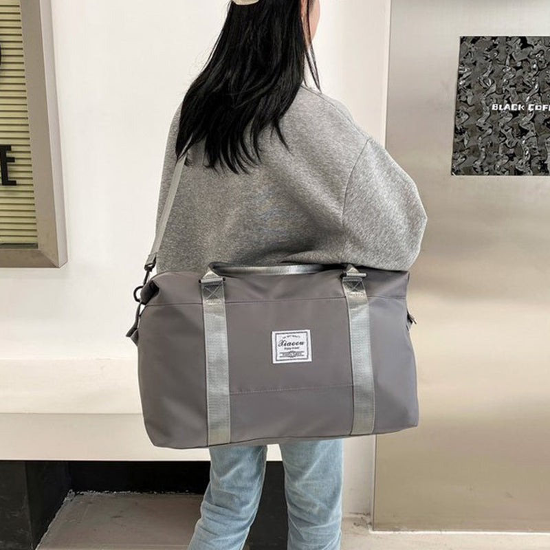 Stylish gray women's travel duffel bag featuring sturdy straps, perfect for carrying essentials