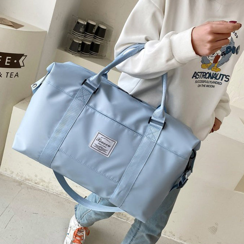 Light blue women's travel duffel bag with sturdy handles and adjustable shoulder strap