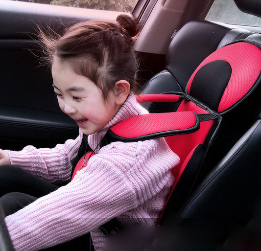 Box of Pandora portable baby car seat in red and black with safety harness securing a smiling child