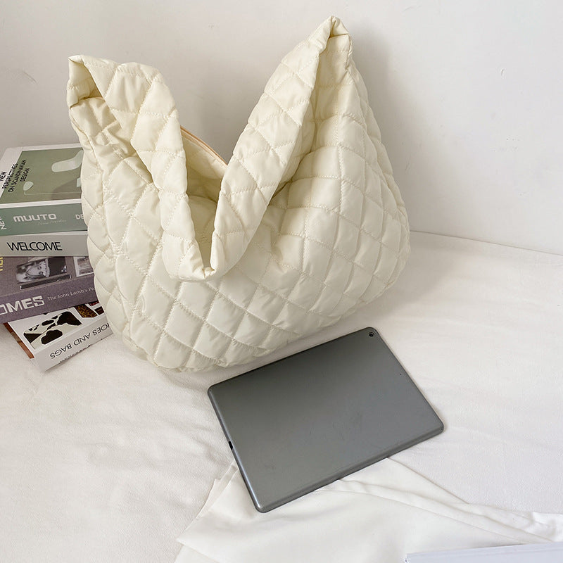 Cream quilted soft warm shoulder bag for women next to a tablet on a white surface