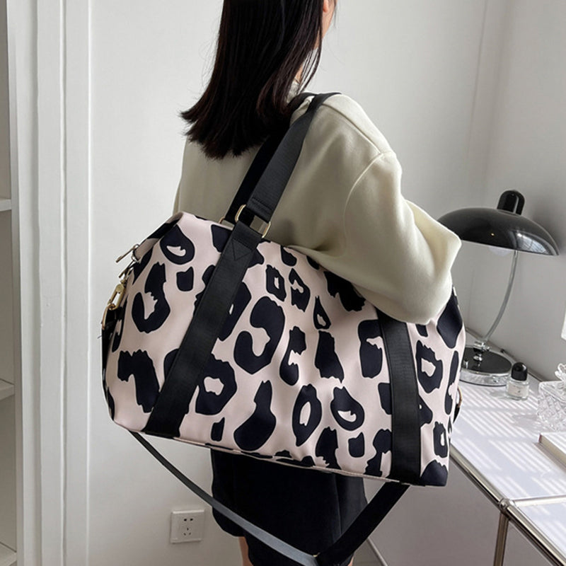 Stylish women’s cow print duffel bag with durable straps, perfect for travel or gym use