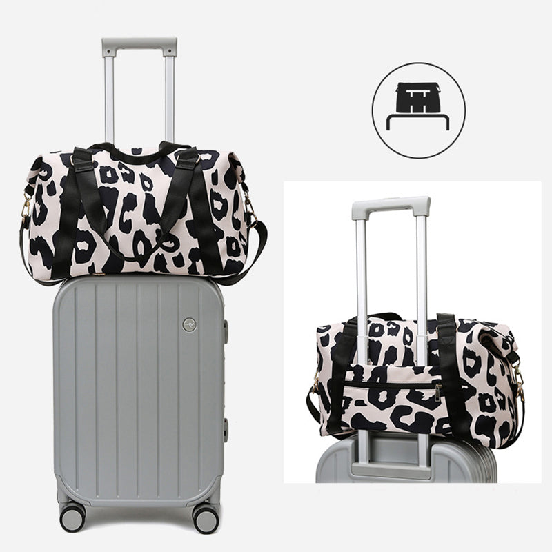Women’s cow print duffel bag on top of a gray suitcase with adjustable straps and stylish design
